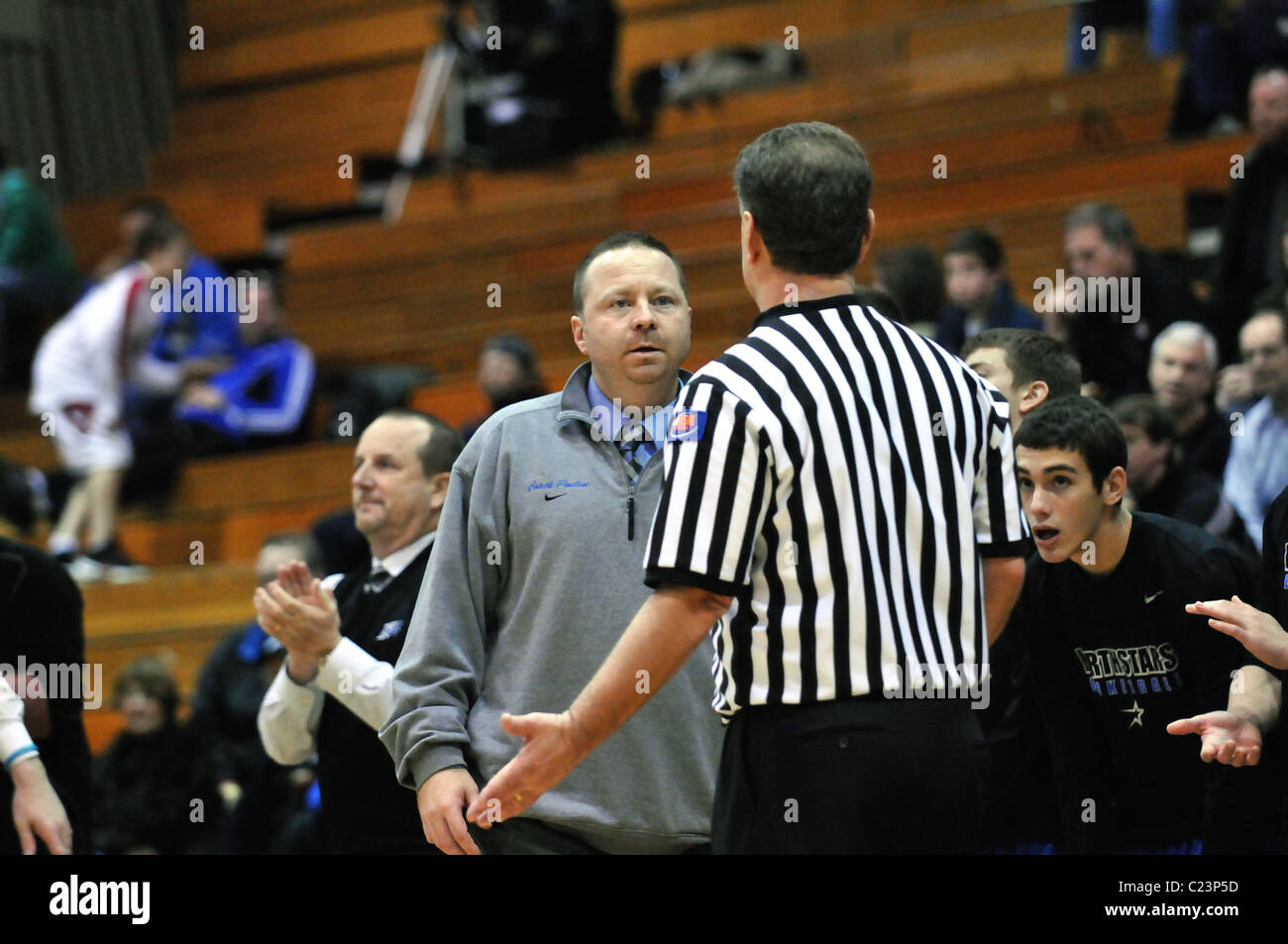 Coach questions an official about a call following a change of possession ruling during a high school basketball game. USA. Stock Photo
