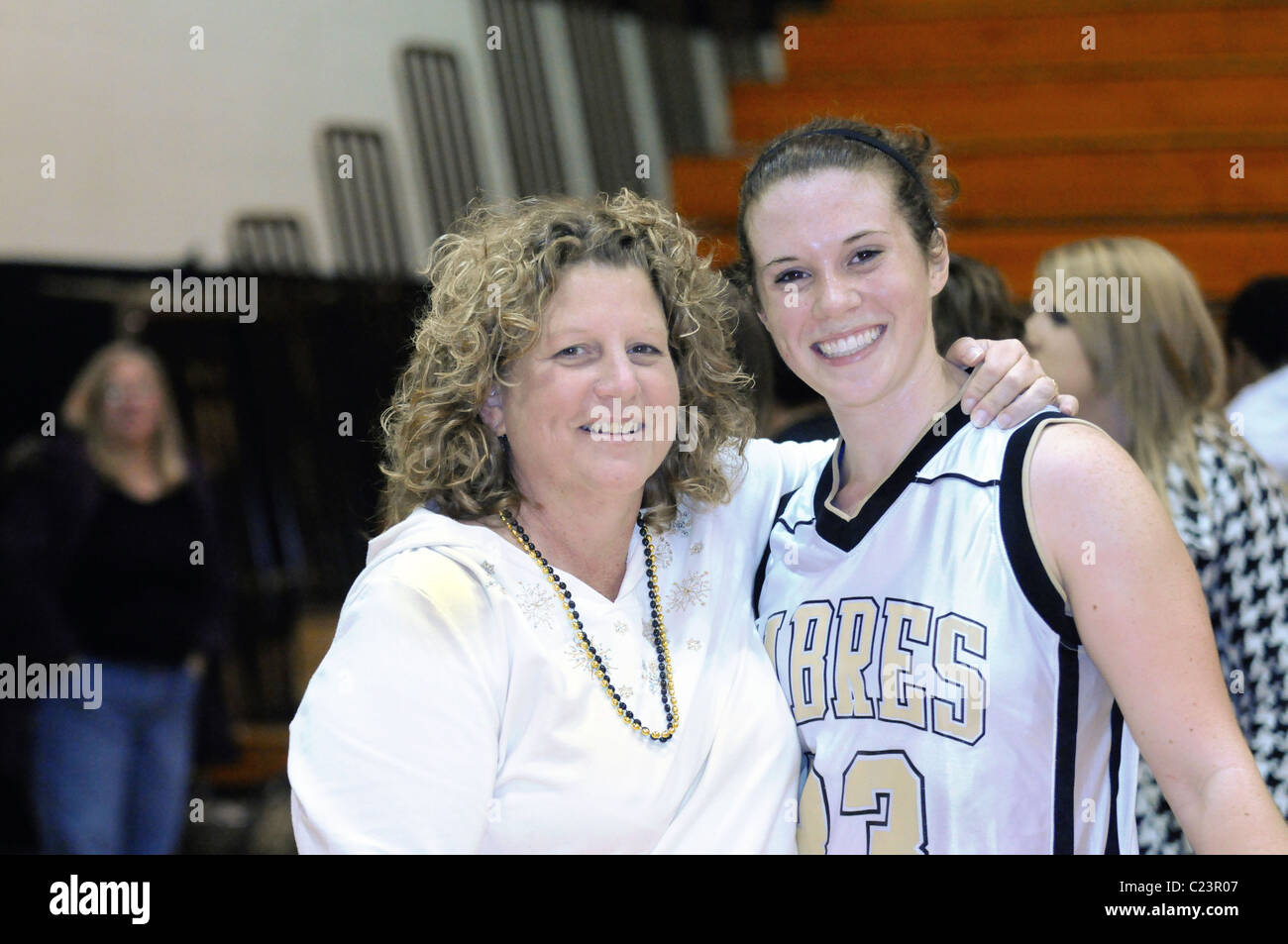 Mother embraces daughter as they share a celebratory moment celebrating the players record 1,000th high school career point. USA. Stock Photo