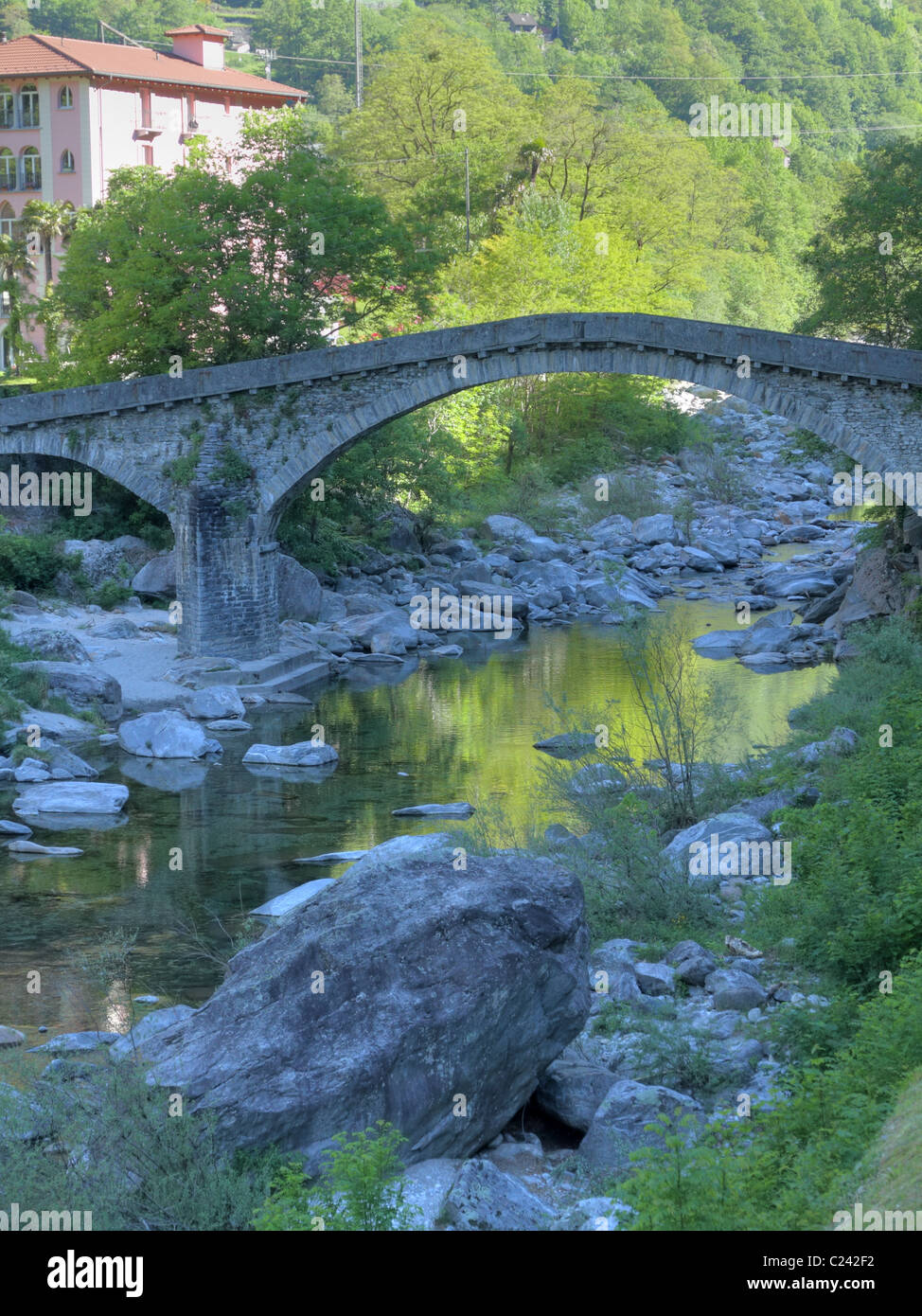 curved famous stone bridge crossing river Maggia in the Ticino mountain village Bignasco in Switzerland Stock Photo