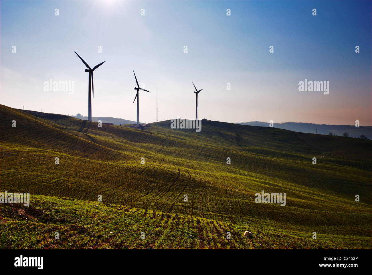 Three wind turbines silhouettes on top of hill Stock Photo - Alamy