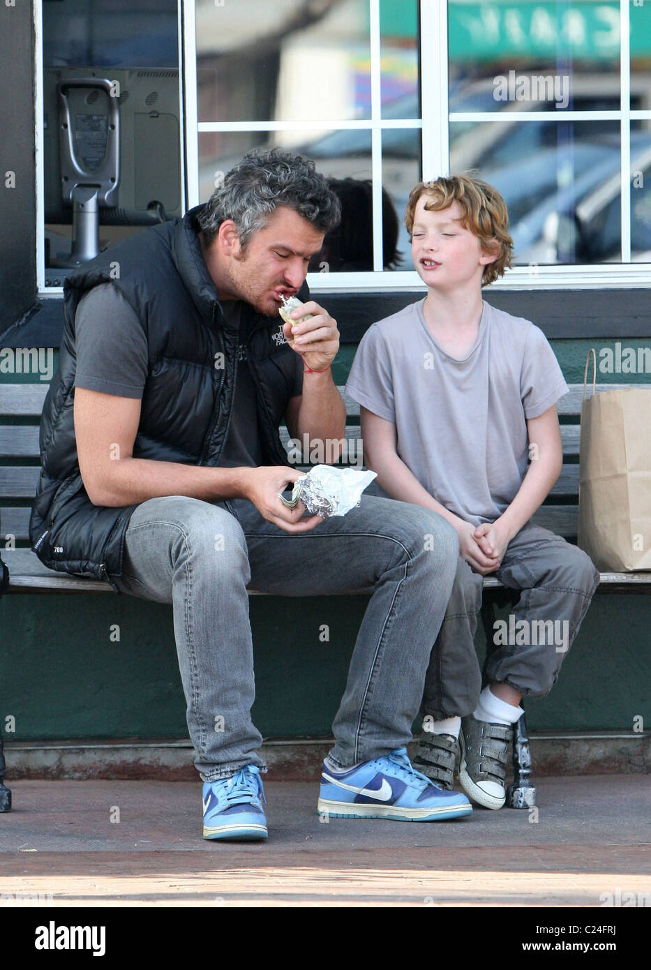 Balthazar Getty holding a wad of dollar bills and eating on a bench in Cross Creek, Malibu with a his son, Cassius Paul Los Stock Photo