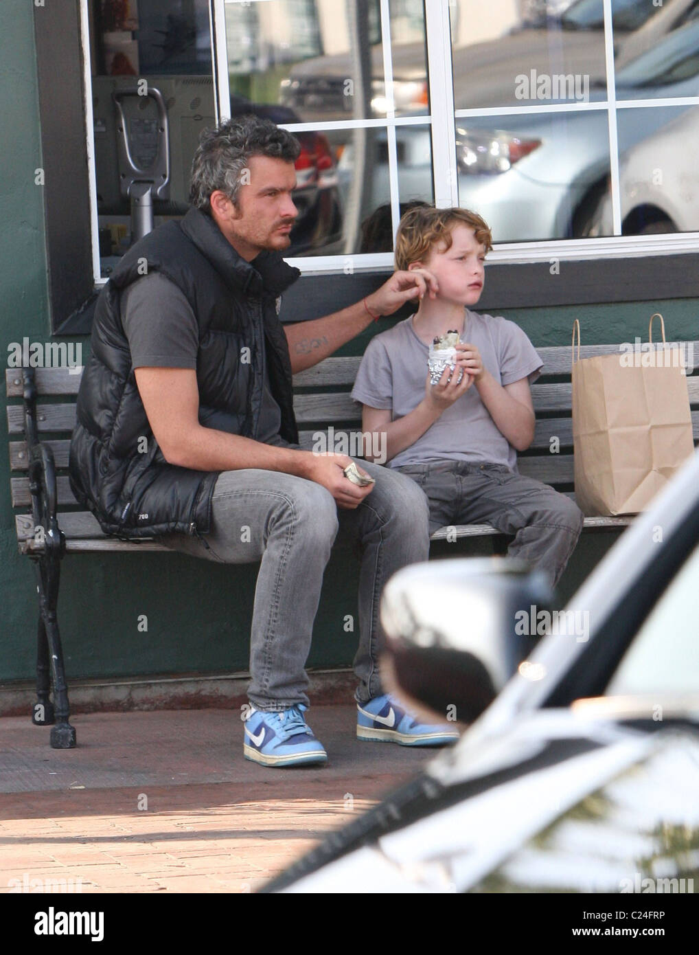 Balthazar Getty holding a wad of dollar bills and eating on a bench in Cross Creek, Malibu with a his son, Cassius Paul Los Stock Photo