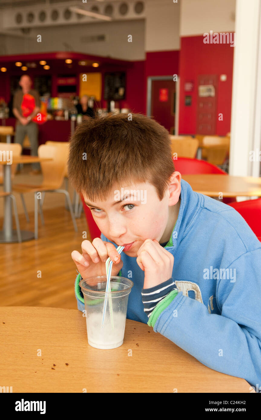 A boy drinking a milkshake in Sainsburys cafe at Longwater Retail Park in Norwich , Norfolk , England , Britain , Uk Stock Photo