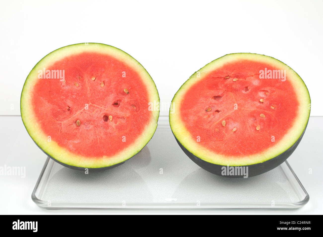 A dark green organic watermelon cut in half Stock Photo Alamy