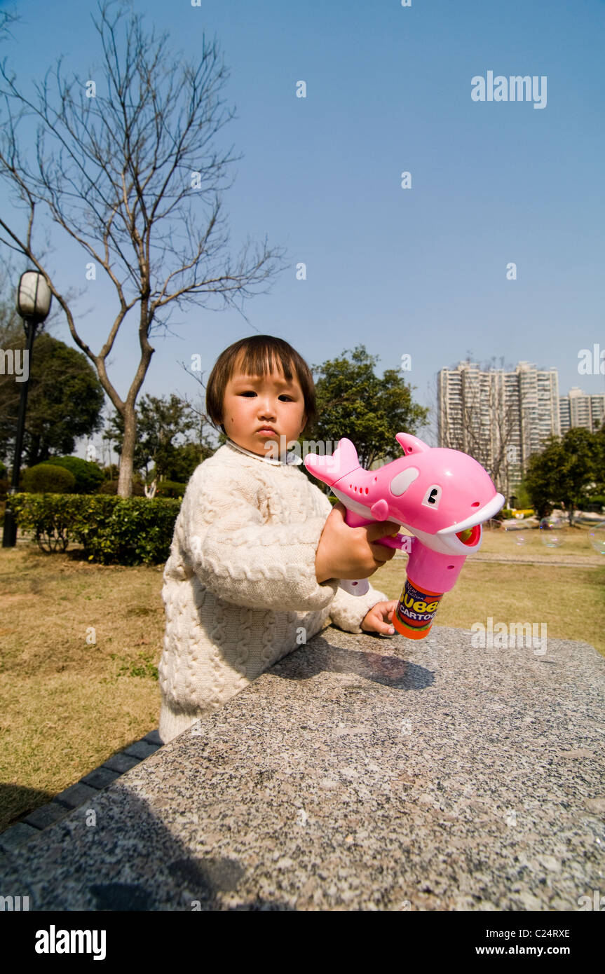 A little Chinese girl playing with a bubble blower Stock Photo - Alamy
