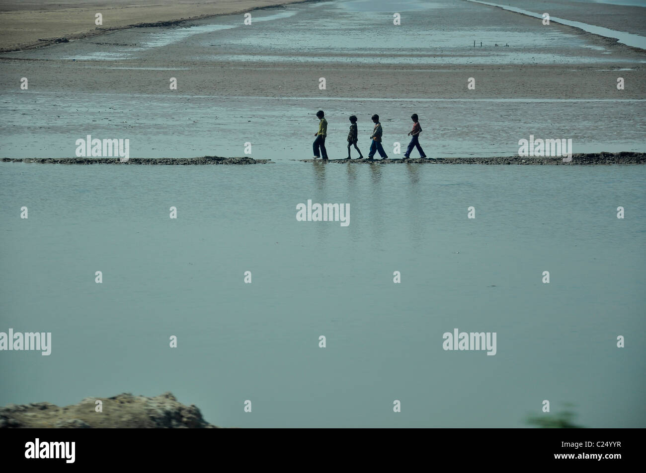 Four people crossing a salt pane in Rann of Kutch, Gujarat, India Stock Photo