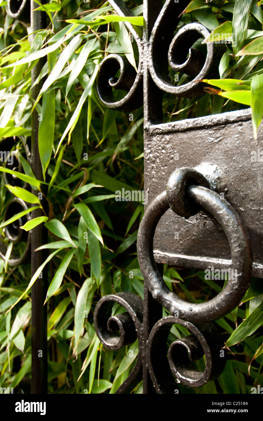 wrought iron gate and ornate handle opening onto a garden with green ...