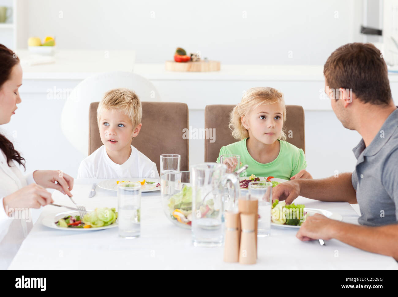 Serious family eating a salad at lunch in the kitchen Stock Photo Alamy