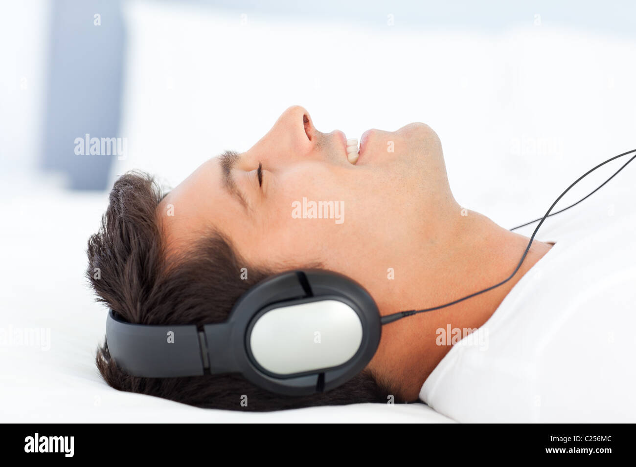 Joyful man listening music lying on his bed Stock Photo
