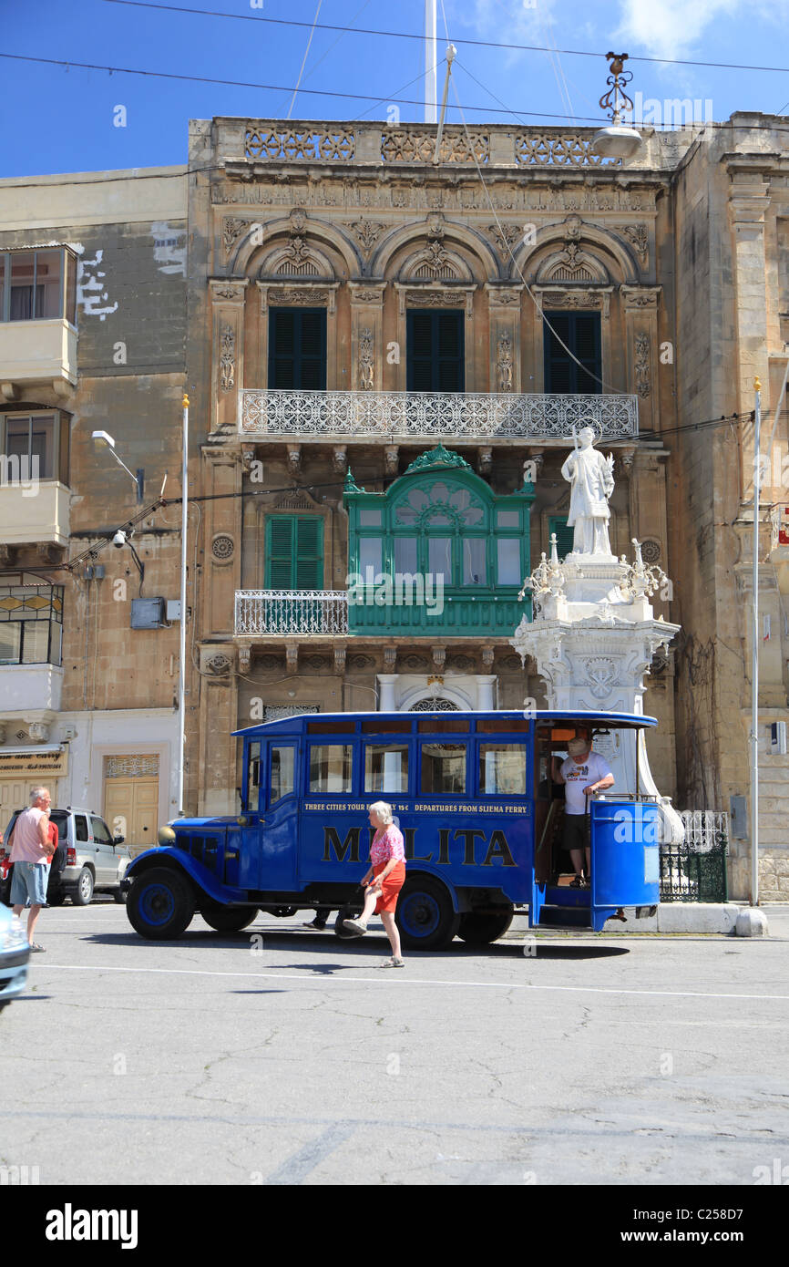malta, mediterranean, blue maltese tour bus standing in front of a traditional colonial building in a town centre Stock Photo