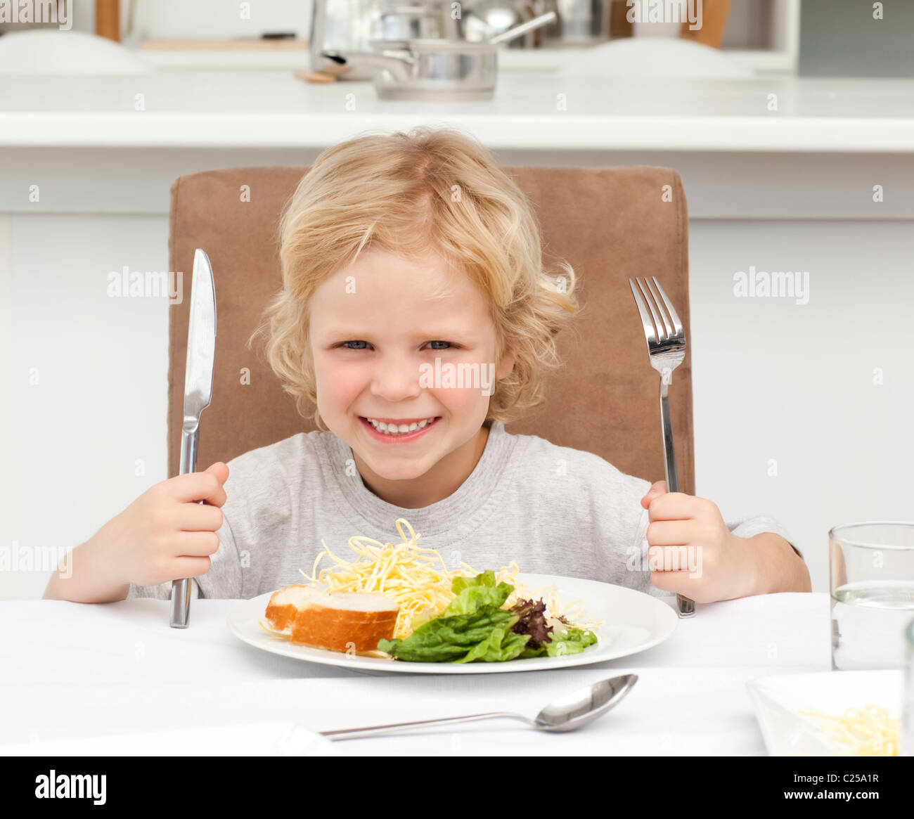Excited boy holding forks to eat pasta and salad Stock Photo Alamy