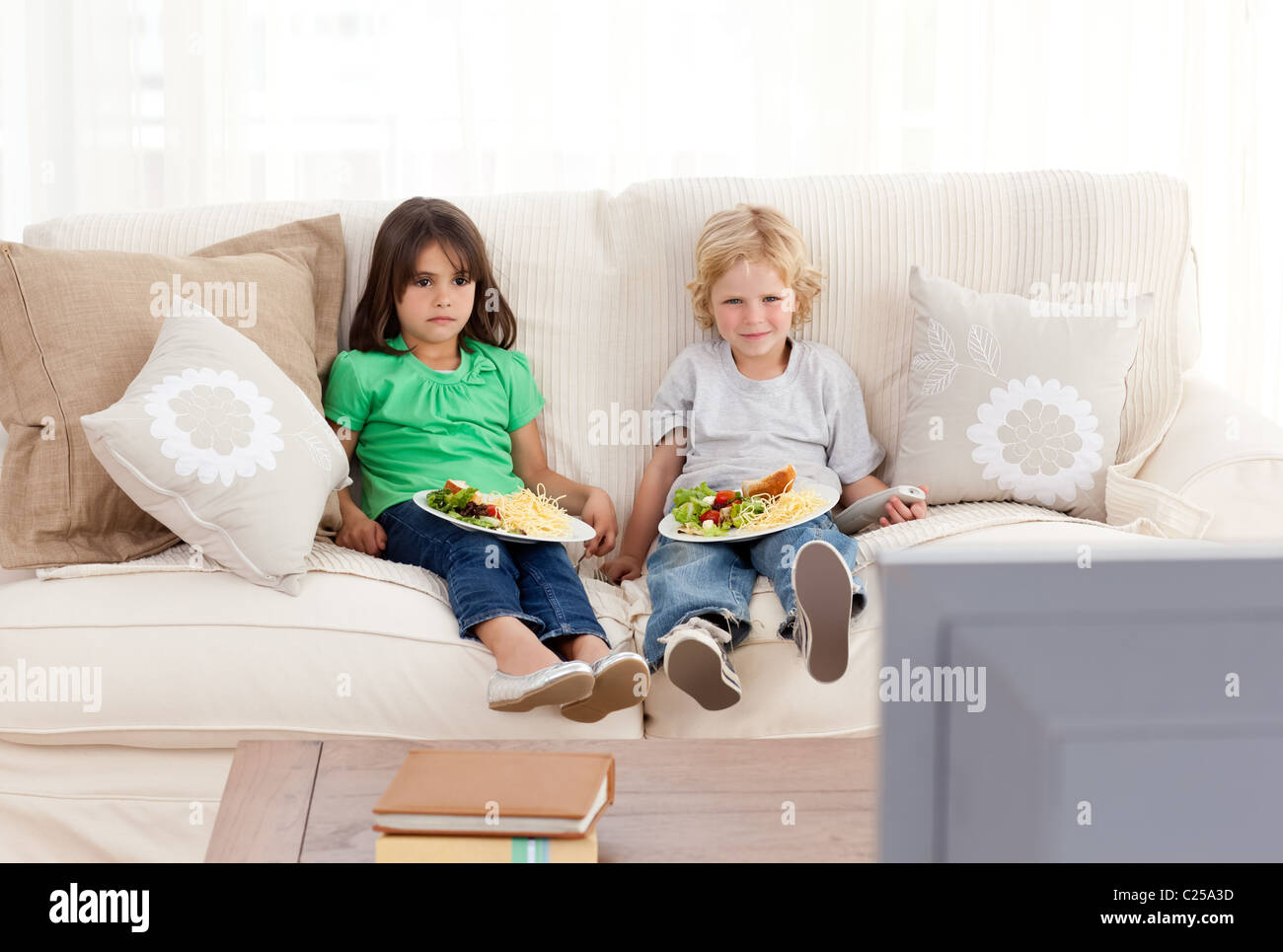 Cute brother and sister having dinner on the sofa Stock Photo - Alamy