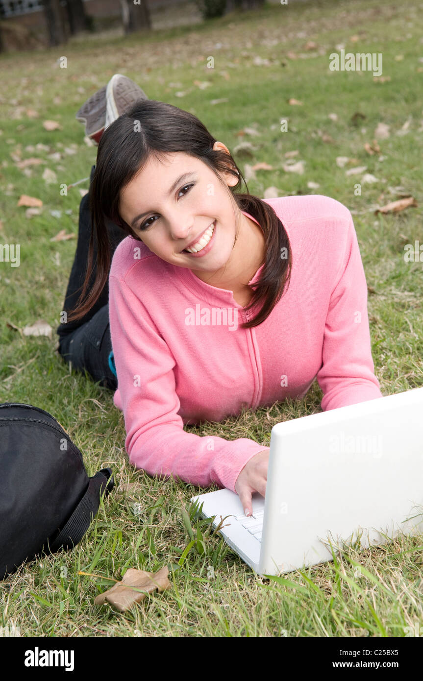 woman, lay, laying, down, on, a, the, field, campus, field, outdoors, park, exteriors, with, mac, laptop, netbook, notebook. Stock Photo