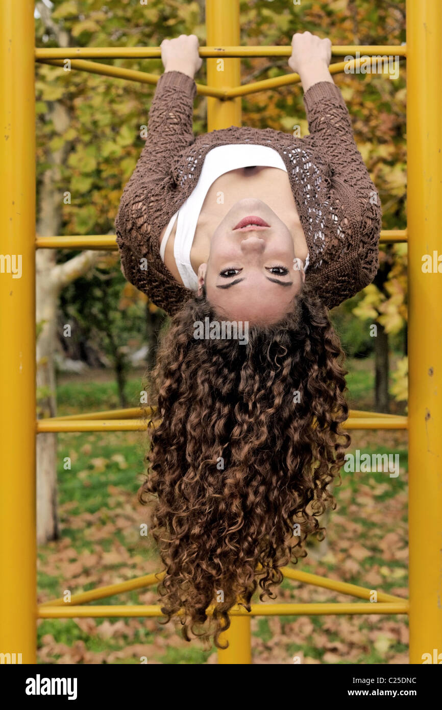 Curly Brown Haired Girl Hanging Upside Down In An Outdoor