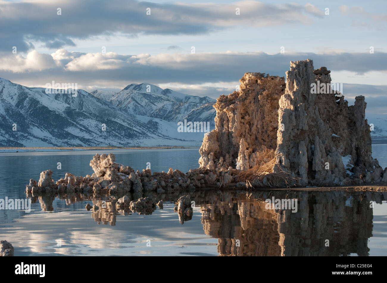 Calcium formed tufa structures emerge from the western Hemisphere's oldest continuously filled salt lake against snowy mountains Stock Photo