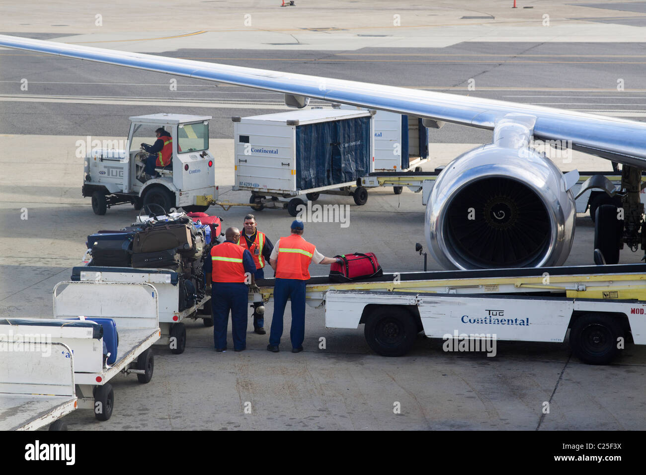 Baggage handlers loading luggage onto a convey into an airplane on the tarmac of New Orleans Airport Stock Photo