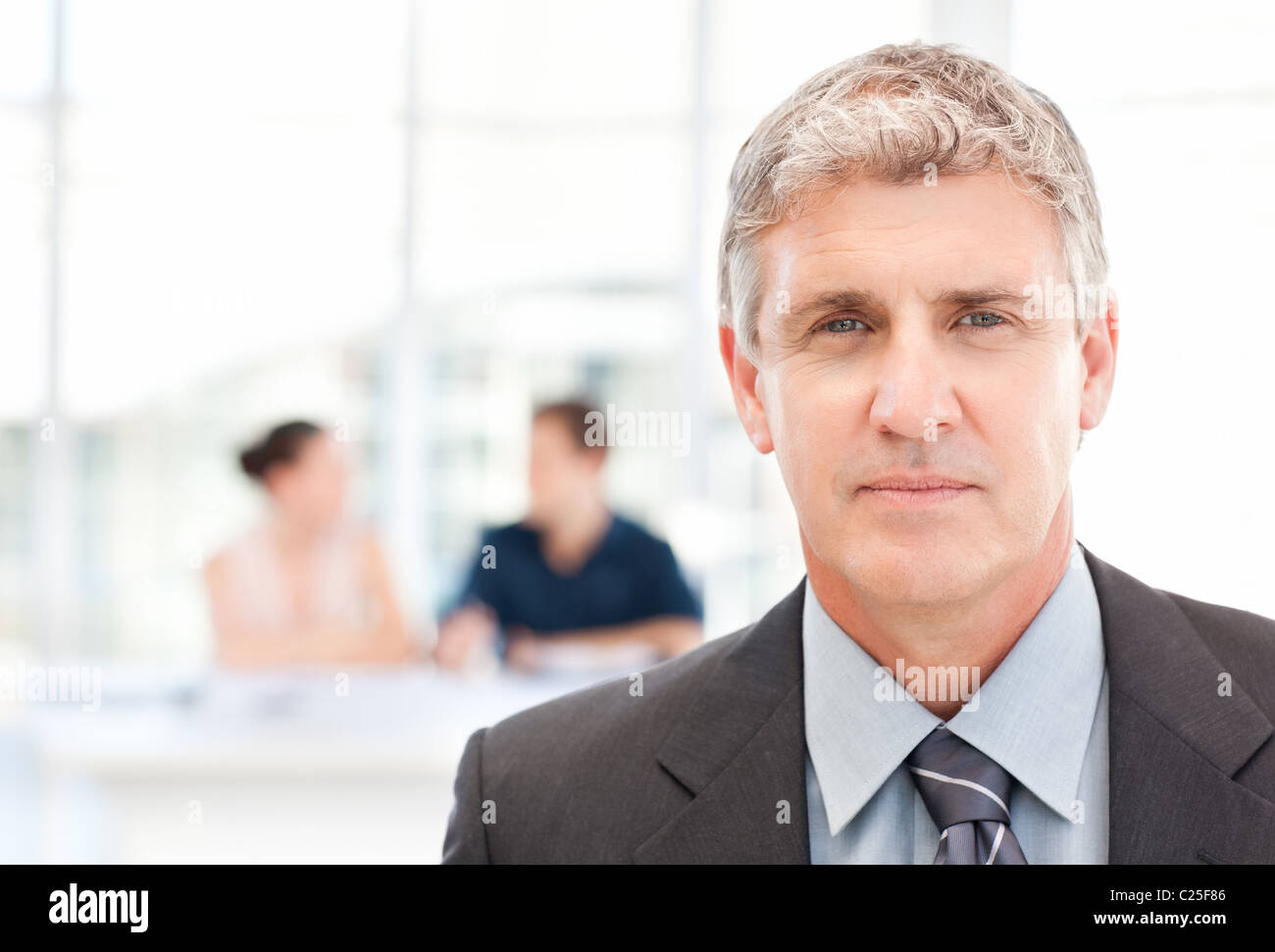 Businessman looking at the camera while his team is working Stock Photo ...