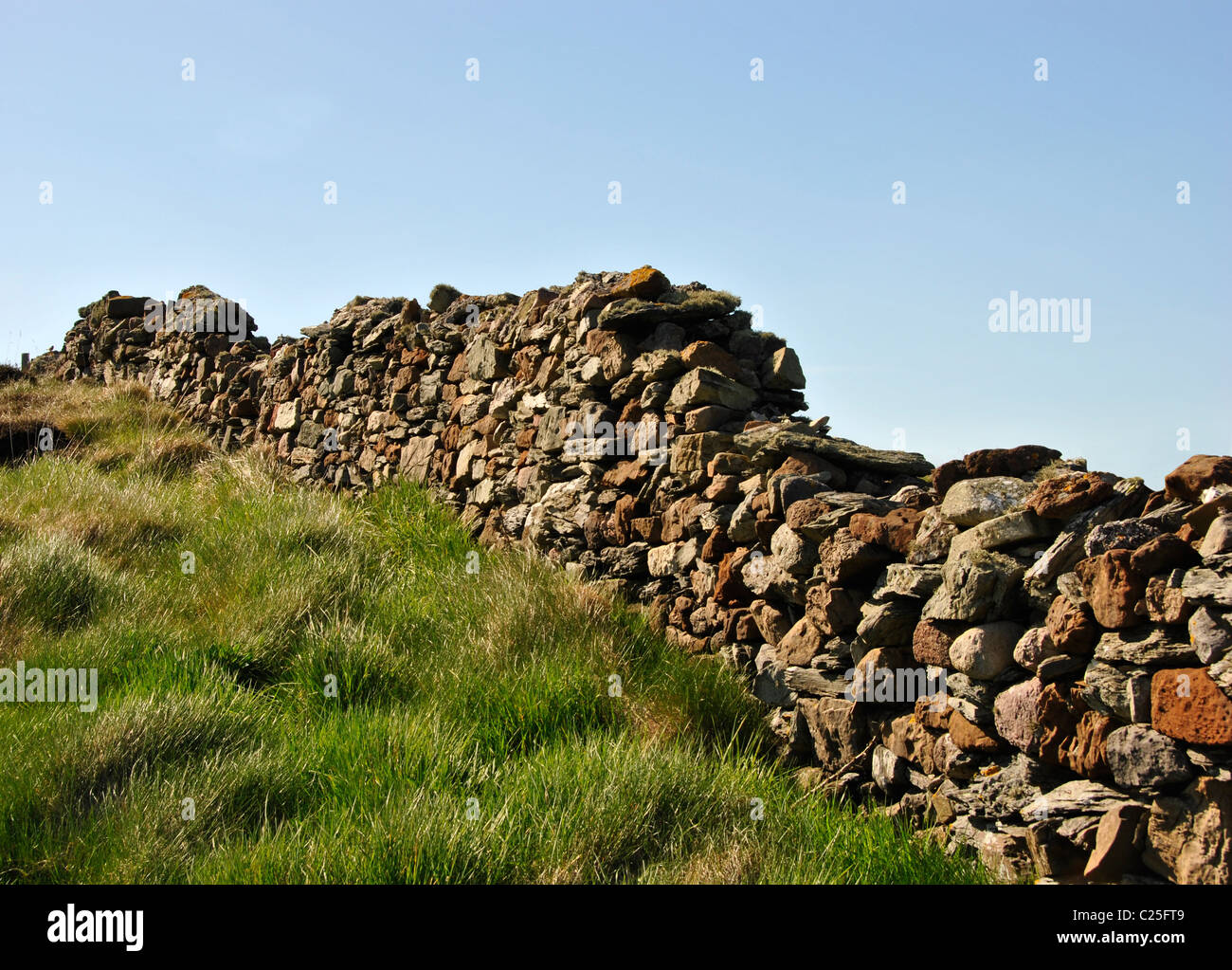 Old stone wall with green grass and light blue sky Stock Photo - Alamy