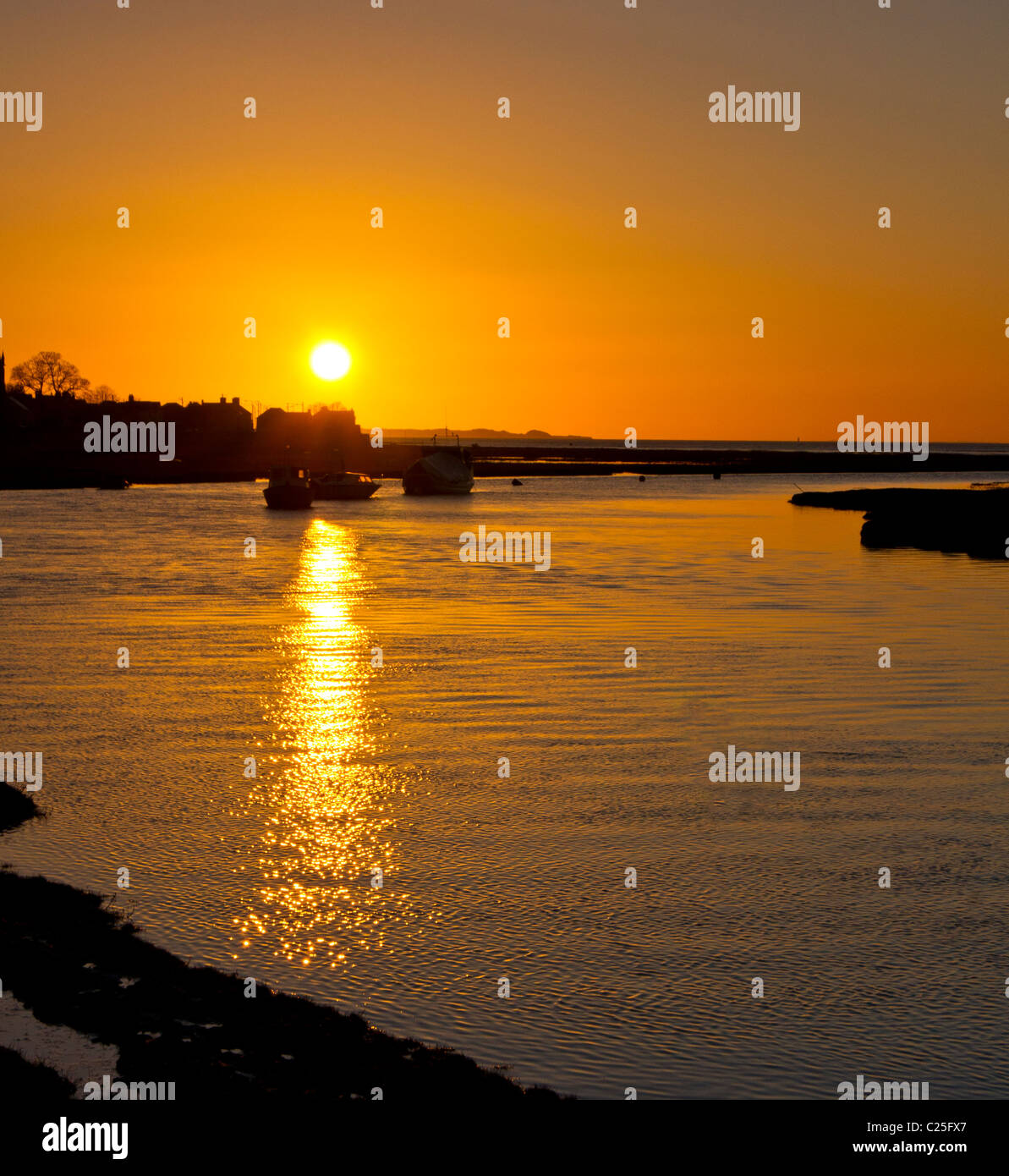 sunset at high tide in penclawdd gower with the sun reflecting on the water Stock Photo