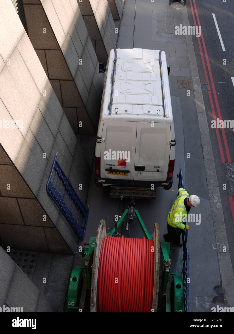 Telecoms workman preparing to install telecoms cabling into road Stock Photo
