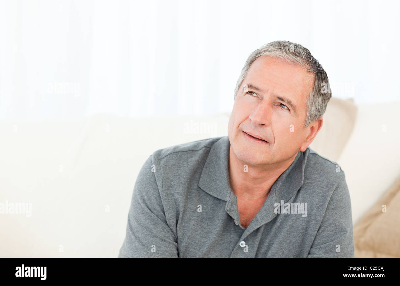 Mature man sitting on a sofa at home Stock Photo - Alamy