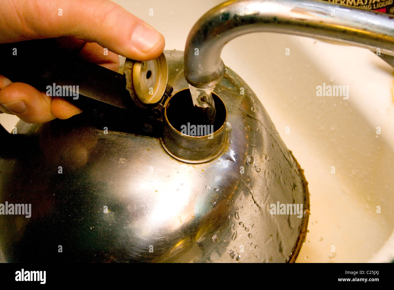 Filling antique old tea kettle with water from the tap. Clitherall