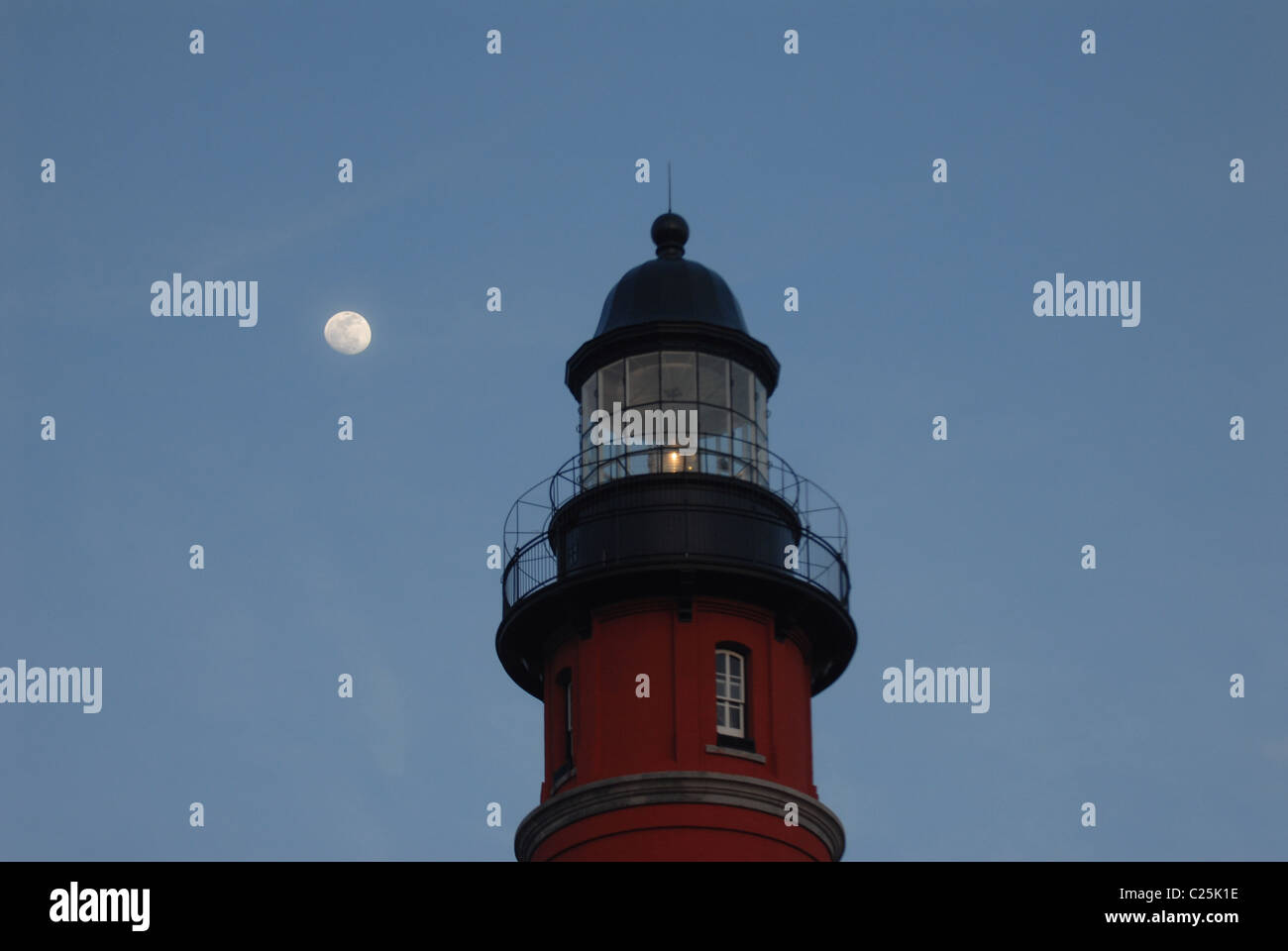 A moon rises behind a lighthouse at Ponce Inlet, Florida Stock Photo
