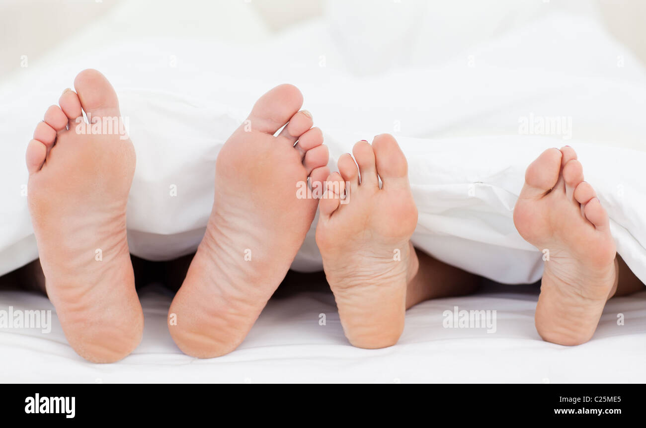 Two members of a family showing their feet while lying on a bed Stock Photo