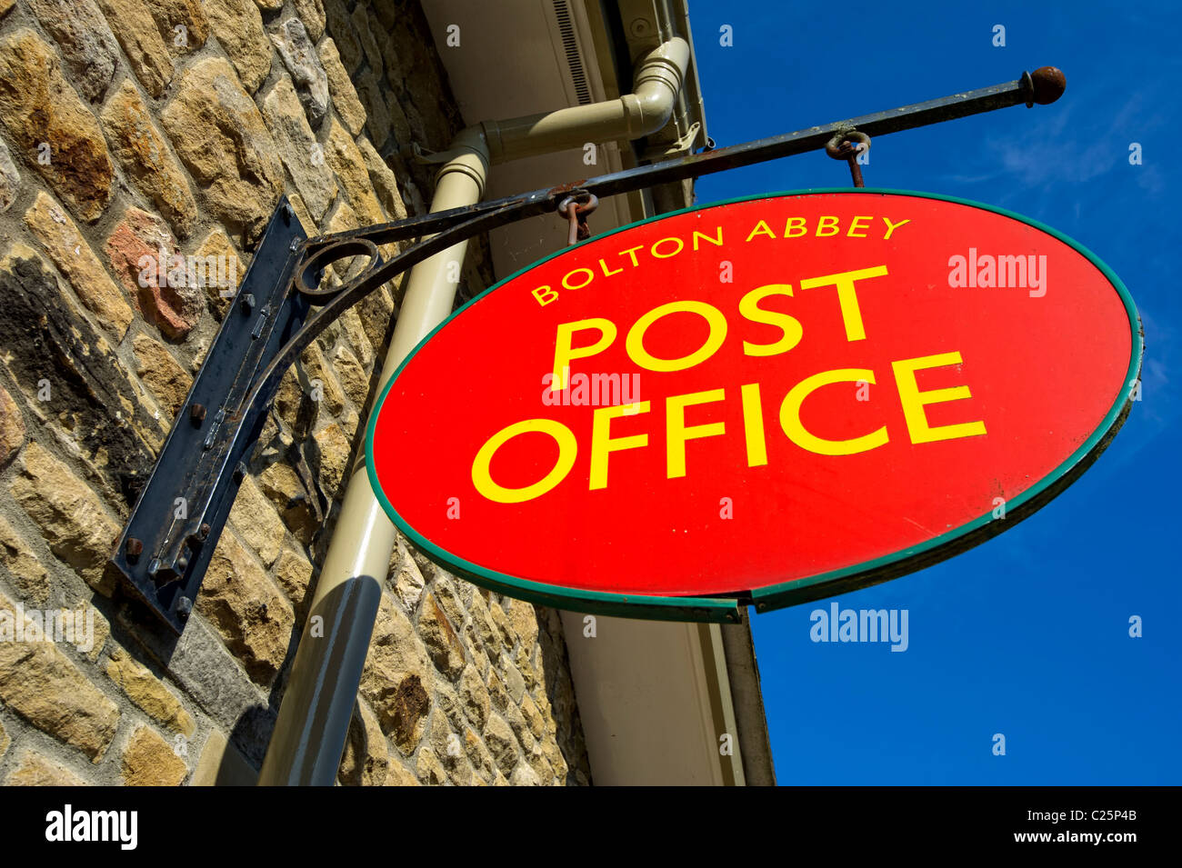 Post Office sign at Bolton Abbey set against bright blue sky Stock