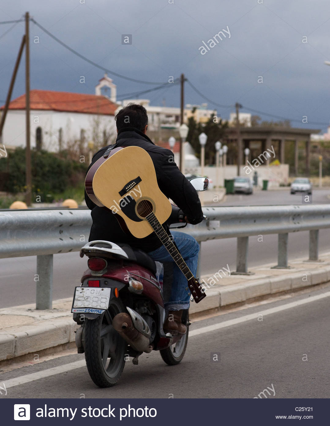 Man riding motorbike without helmet carrying guitar Stock Photo
