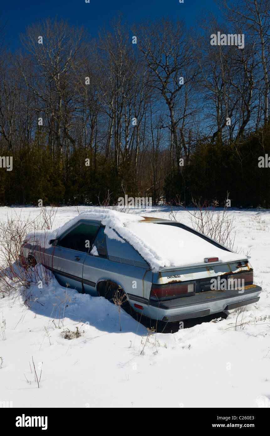 Abandoned Dodge Chrysler car in a snow covered field on a clear winter day Ontario Stock Photo