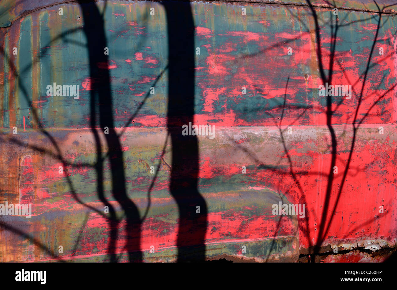 Colorful side of abandoned truck in forest looking like red sunset on a blue lake through the trees Stock Photo