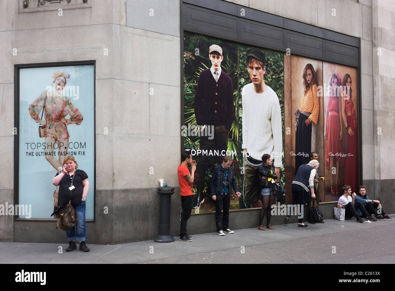 Employees from high street fashion retailer Topshop smoke under ad posters  at the rear of their store Stock Photo - Alamy