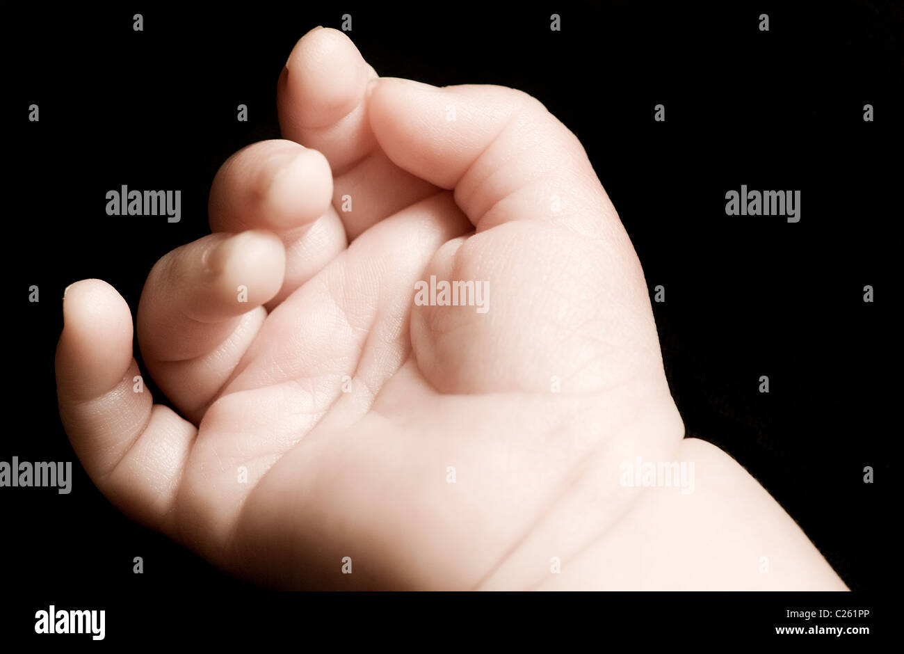 close-up of tiny baby's palm hand against black background Stock Photo