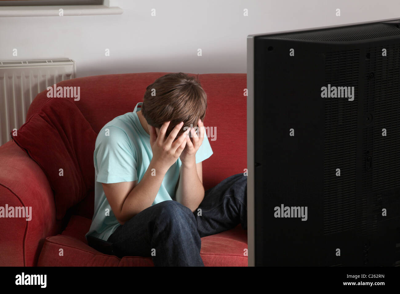 Young male watching TV sport at home head in hands. Stock Photo