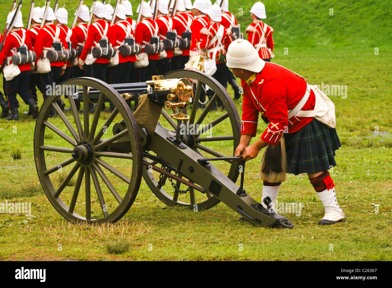 A man wearing the uniform of The Gordon Highlanders readies a replica Colt Gatling gun during a historical reenactment. Stock Photo