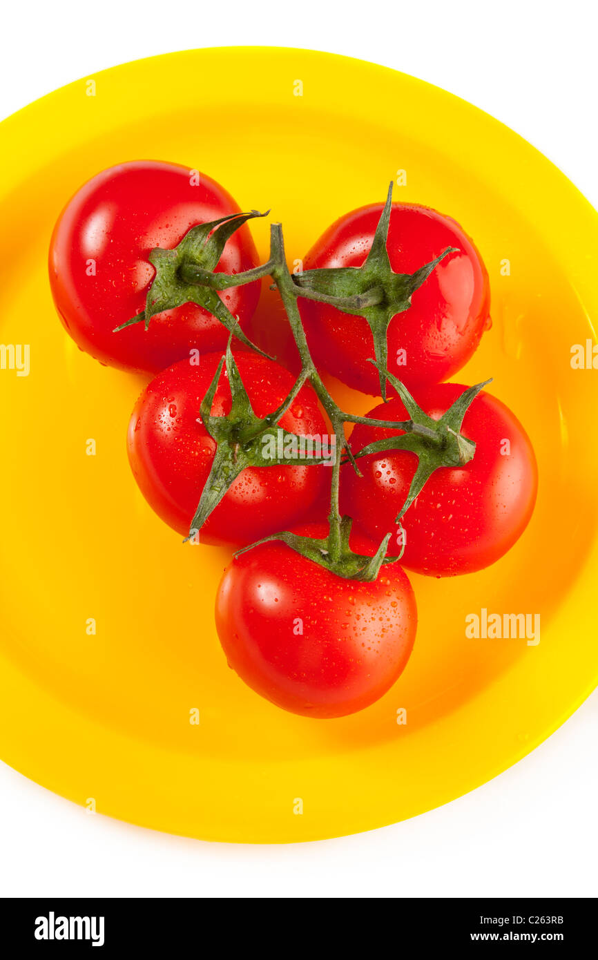 Yellow plate of red tomatoes isolated on white Stock Photo - Alamy
