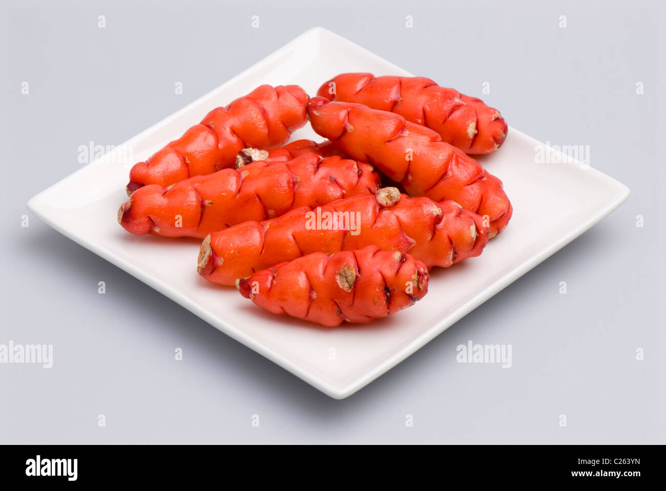 Red yams Oxalis tuberosa on a square white plate dish. White background. Stock Photo