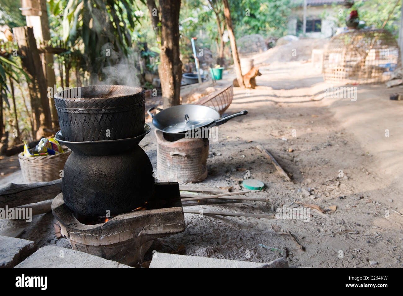Traditional stick rice steaming over an open fire pot on a farm in Isan North East Thailand Stock Photo