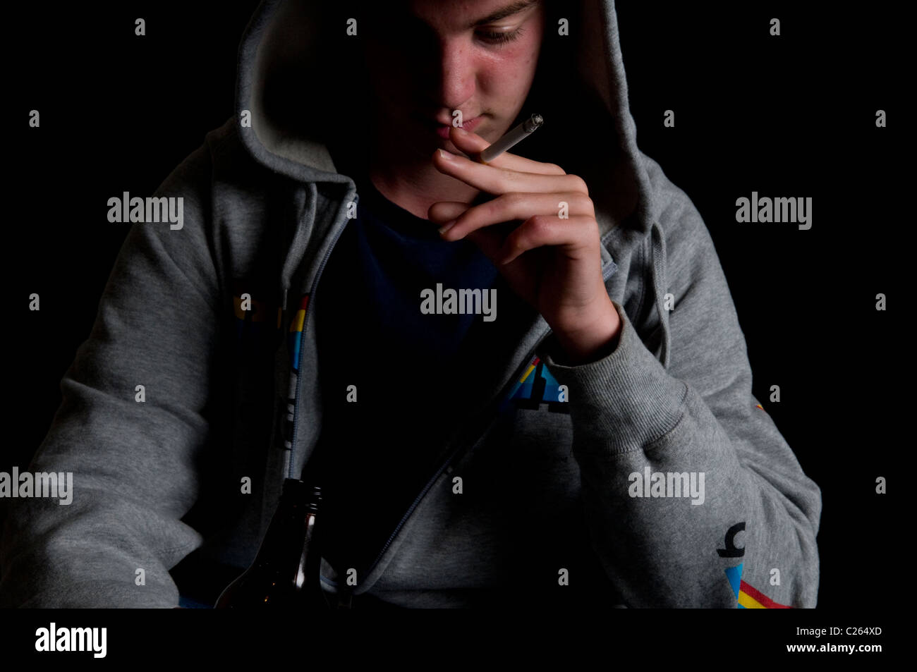 Teenaged boy in hoody smoking and drinking Stock Photo