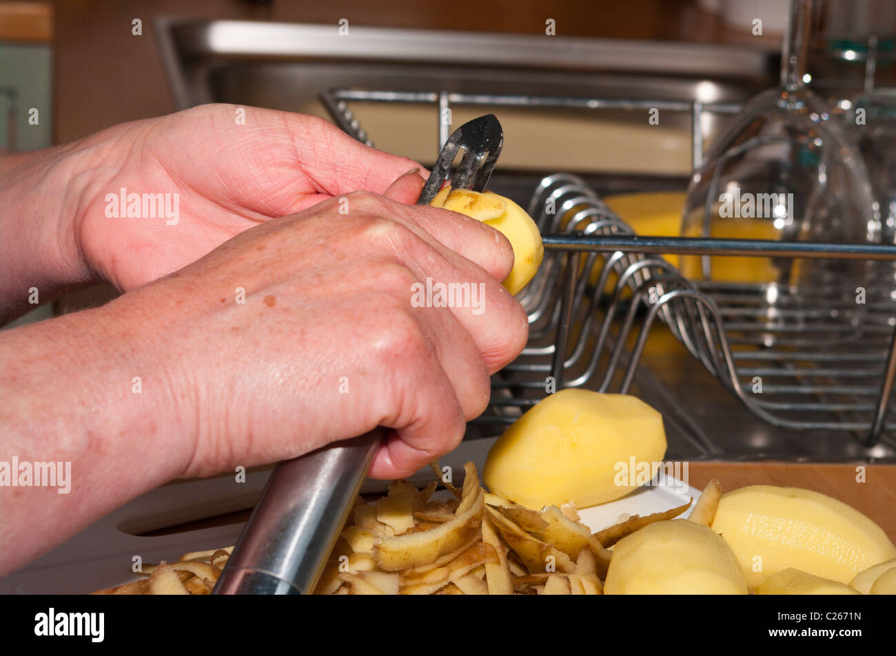Woman Peeling A New Potato With A Potato Peeler Stock Photo Alamy