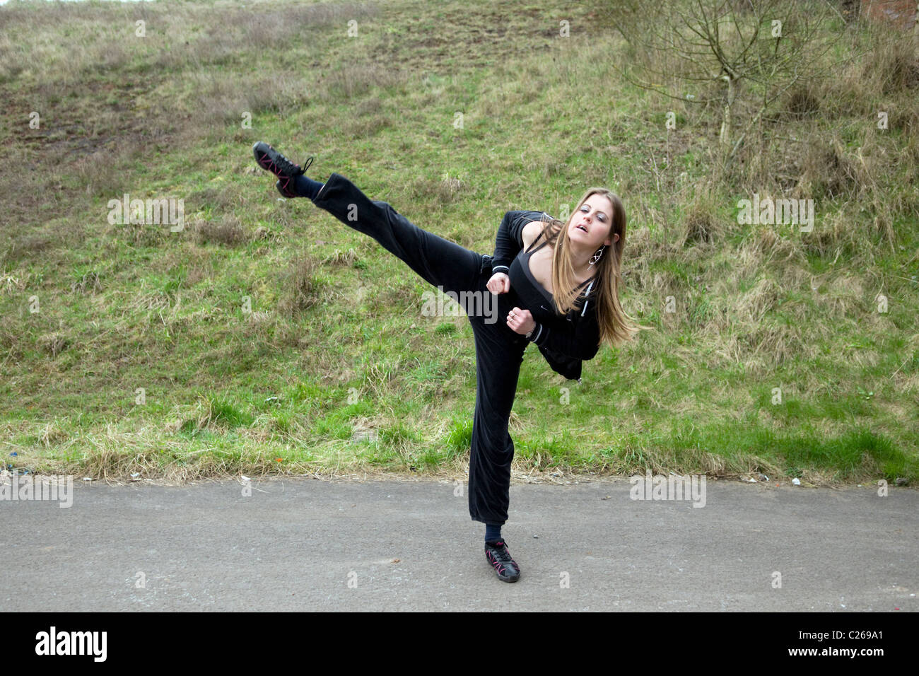 Young Caucasian woman doing a tae kwon do kick outside, taken in Emersons Green, Bristol Stock Photo