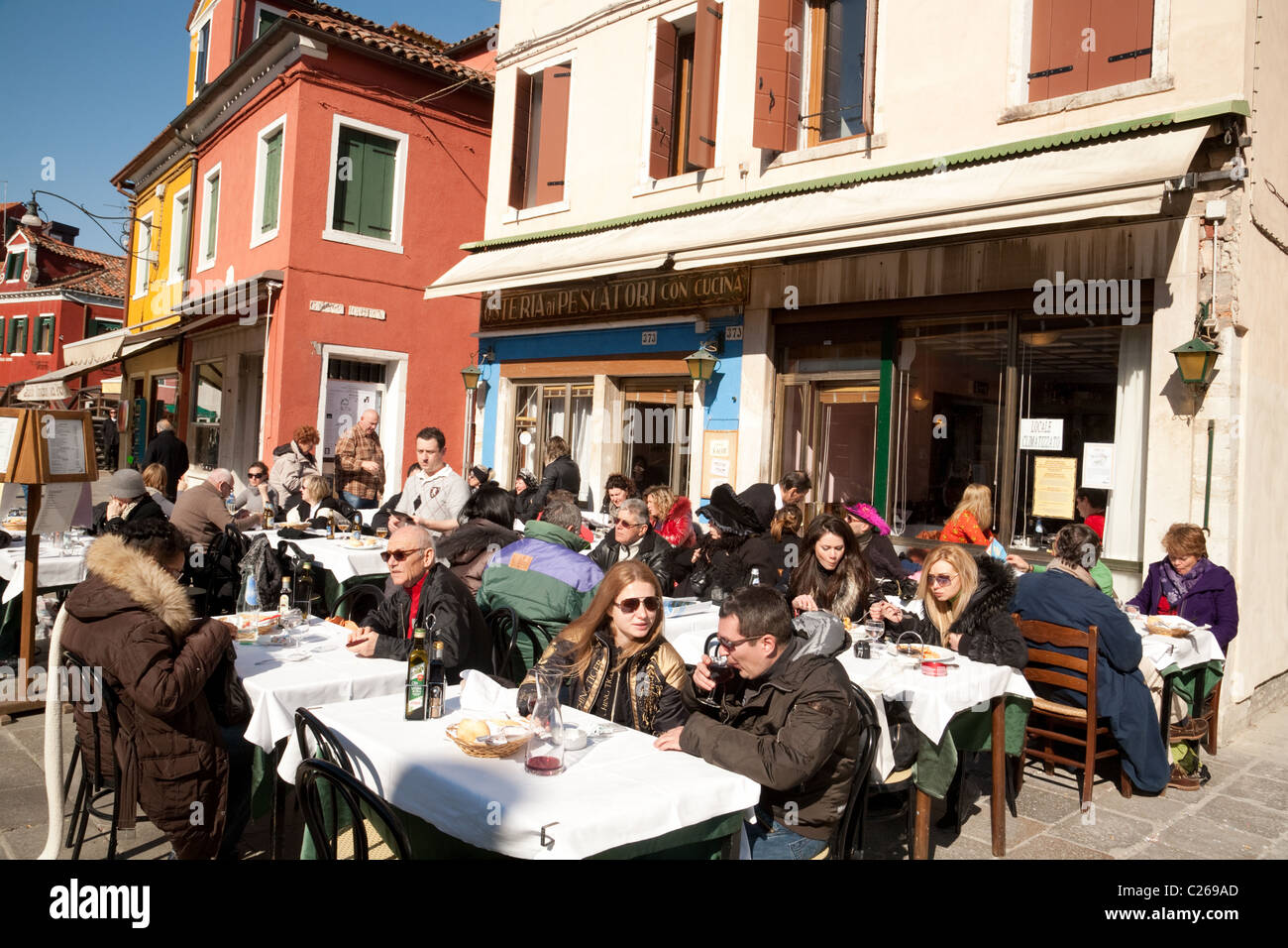 people eating and drinking at an outdoor restaurant, Burano village, Venice, Italy Stock Photo