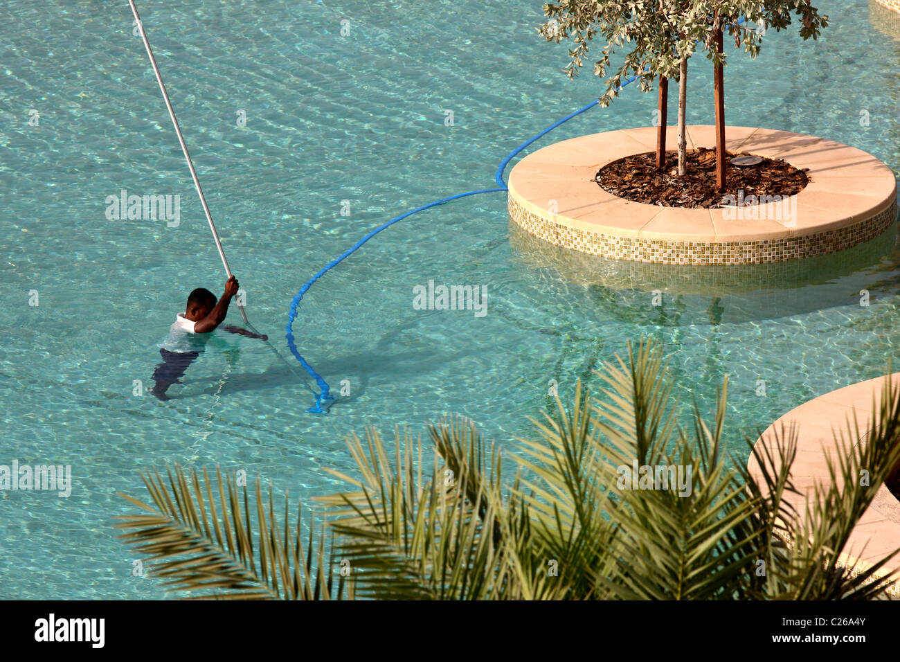 A swimming pool is cleaned by hotel staff with special underwater vacuum cleaners. Stock Photo