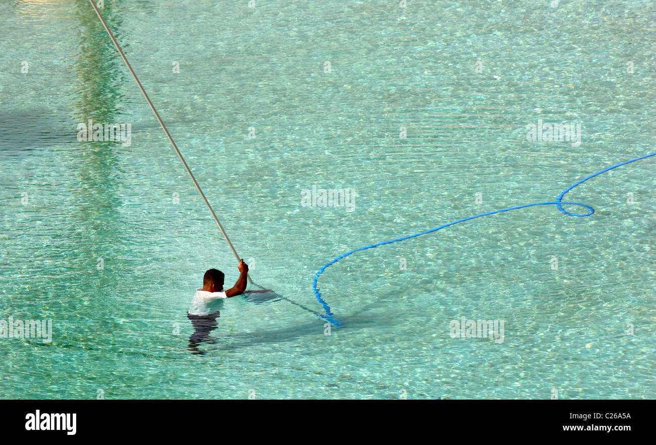 A swimming pool is cleaned by hotel staff with special underwater vacuum cleaners. Stock Photo