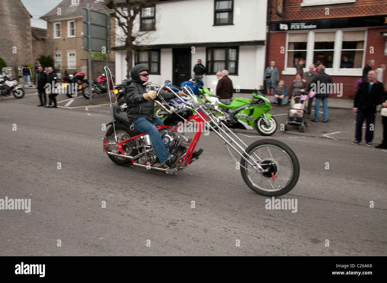Motorcycle rider on his chopper riding along Wootton Bassett High Street as part of the Ride of Respect to raise charity funds Stock Photo