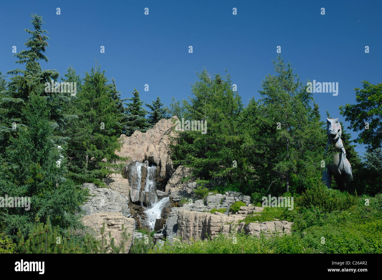 A scene of the Calgary Zoo prehistoric park with a tyrannosaurus rex and waterfall. Stock Photo