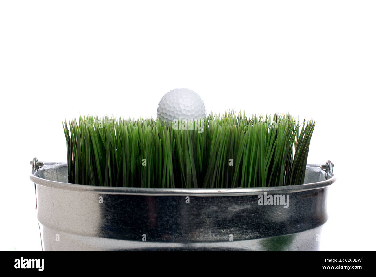 Horizontal image of a golf ball on grass in a small container on white. Container gardening Stock Photo