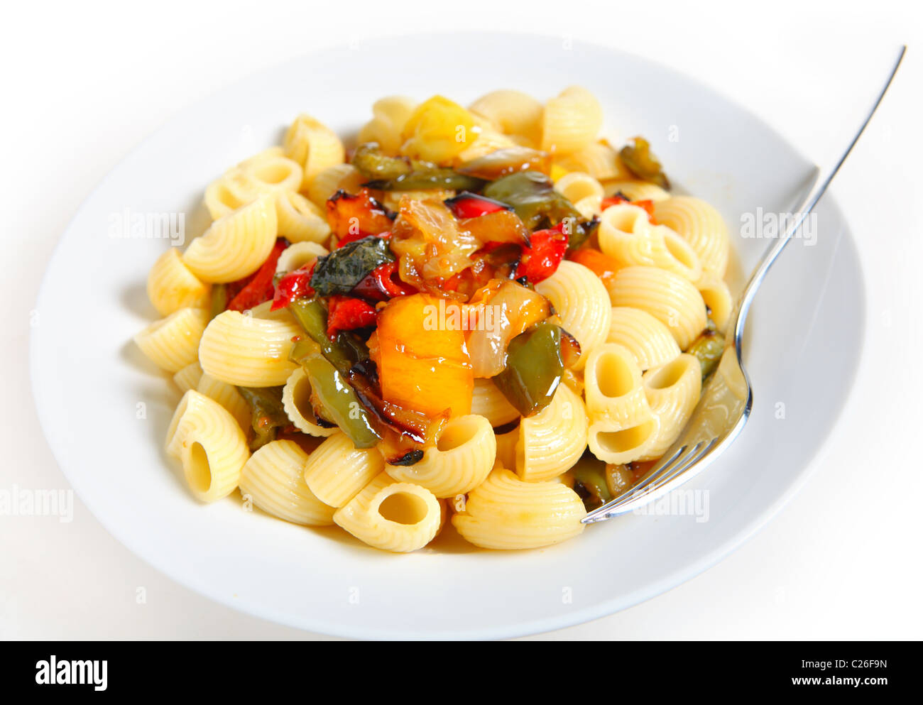 A bowl of pasta tubes with served with roasted peppers, onion and cherry tomatoes Stock Photo