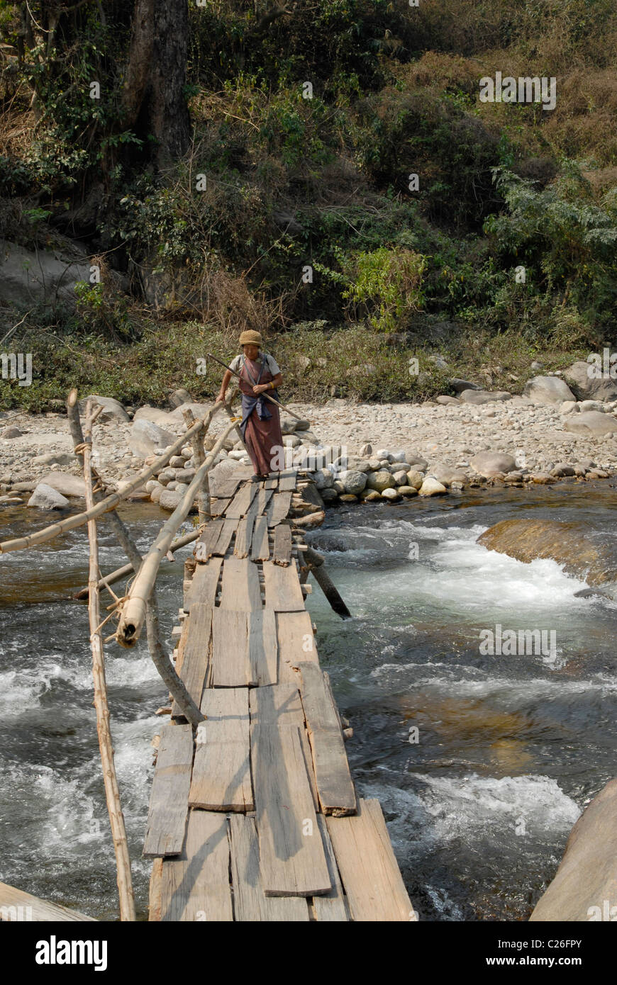 Bhutanese woman passing a dangerous footbridge at Lingmethang (near Mongar), Bhutan Stock Photo
